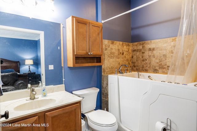 bathroom featuring a washtub, vanity, tile walls, washer / clothes dryer, and toilet