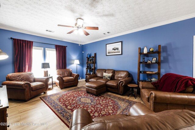 living room featuring ceiling fan, light hardwood / wood-style floors, crown molding, and a textured ceiling