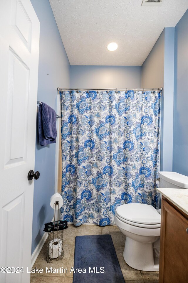 bathroom with vanity, a textured ceiling, tile patterned flooring, toilet, and curtained shower