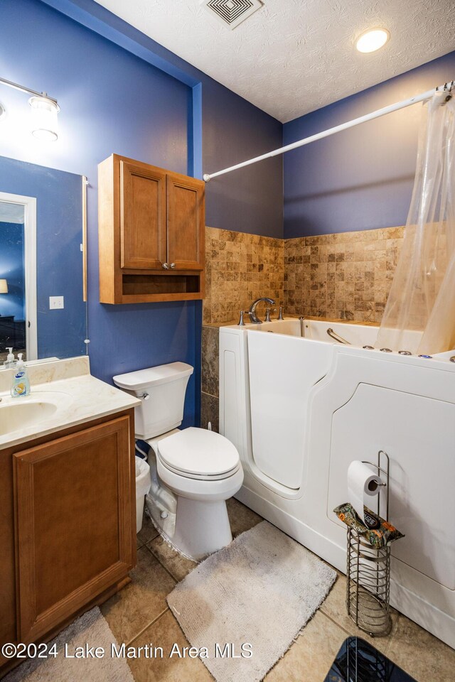 bathroom featuring a tub to relax in, tile patterned flooring, a textured ceiling, and toilet