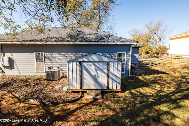 rear view of house featuring a yard, central AC, and a shed