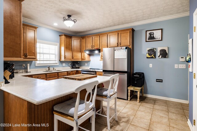 kitchen featuring a breakfast bar area, crown molding, a textured ceiling, and appliances with stainless steel finishes