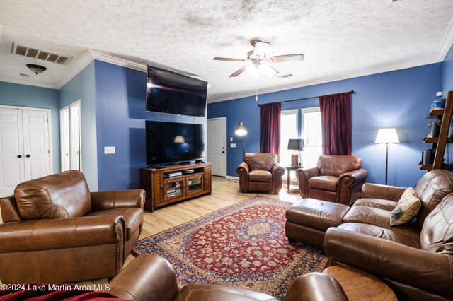 living room with ceiling fan, ornamental molding, a textured ceiling, and light wood-type flooring