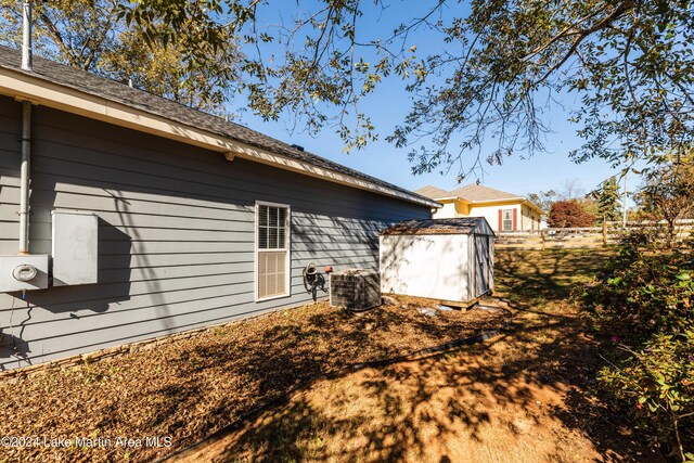 view of property exterior with central AC unit and a shed