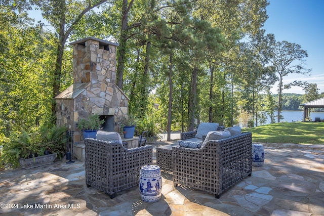 view of patio with an outdoor stone fireplace and a water view