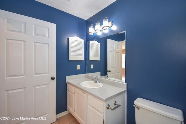 bathroom with toilet, vanity, tile patterned flooring, and a textured ceiling