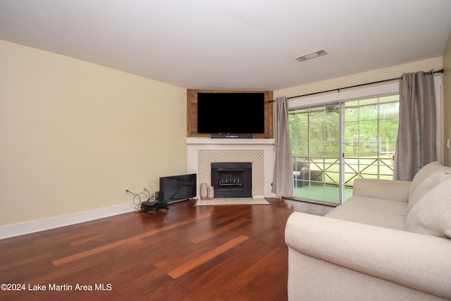 living room with wood-type flooring and a tiled fireplace