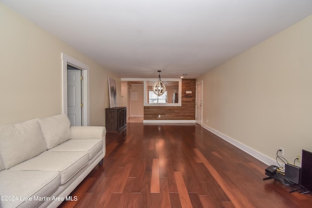 unfurnished living room featuring dark hardwood / wood-style floors, wood walls, and a chandelier