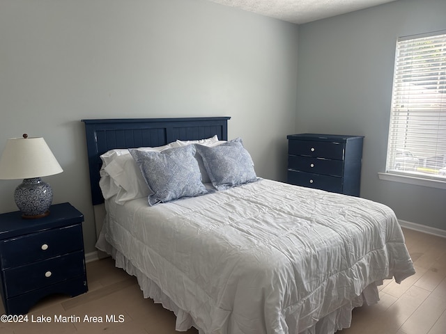 bedroom featuring light wood-type flooring, a textured ceiling, and multiple windows