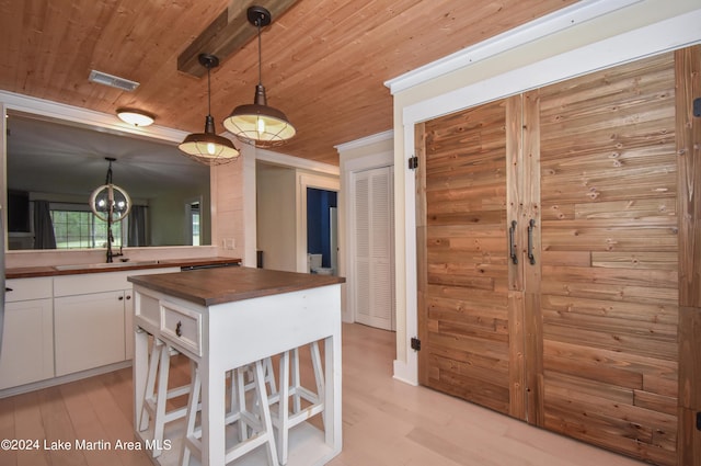 kitchen with wooden ceiling, white cabinets, butcher block countertops, and decorative light fixtures