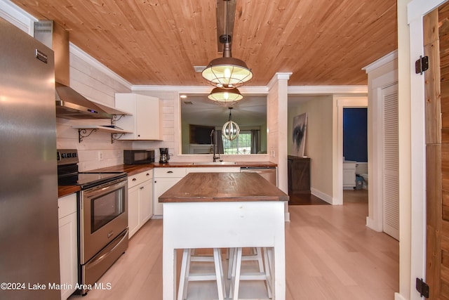 kitchen with white cabinets, appliances with stainless steel finishes, wood counters, and a center island