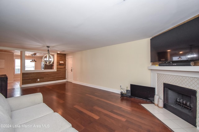 living room with a fireplace, wood walls, a chandelier, and light hardwood / wood-style flooring