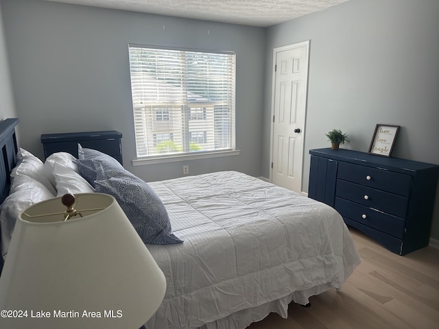 bedroom featuring light wood-type flooring and a textured ceiling