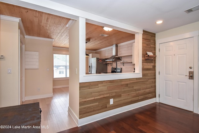 foyer with dark wood-type flooring, wood ceiling, and wooden walls