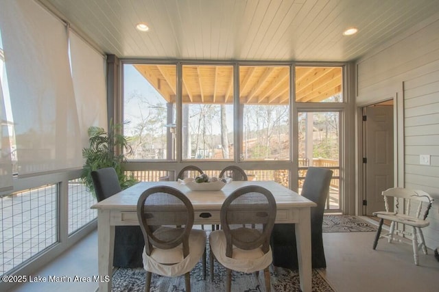 dining room featuring a sunroom, a wall of windows, and a wealth of natural light