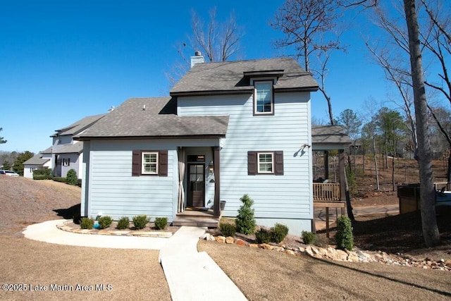 traditional-style home featuring roof with shingles and a chimney