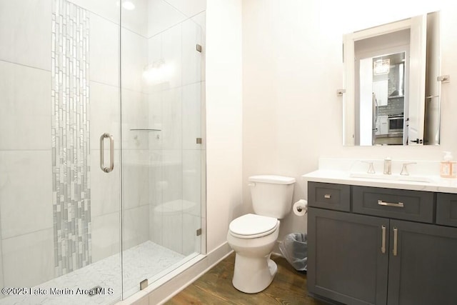 bathroom featuring toilet, a stall shower, wood finished floors, and vanity