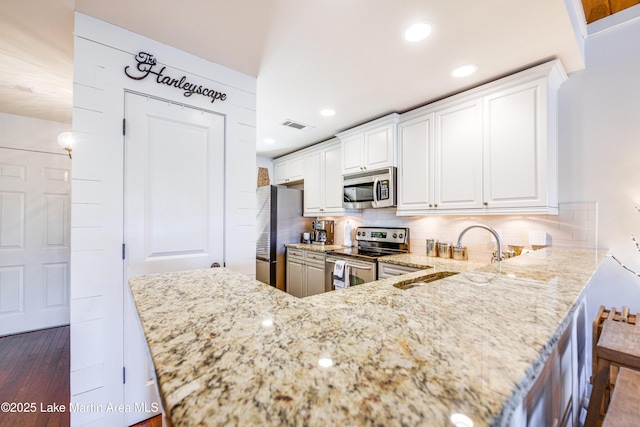 110 Village Loop Unit A103, Dadeville, AL 36853 - kitchen with stainless steel appliances, light stone counters, backsplash, white cabinets, and recessed lighting