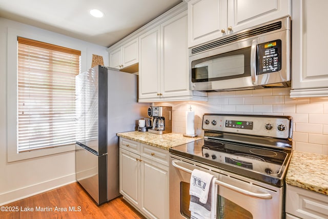 110 Village Loop Unit A103, Dadeville, AL 36853 - kitchen with appliances with stainless steel finishes, light wood-style floors, decorative backsplash, white cabinets, and recessed lighting