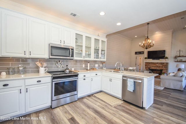 kitchen with decorative backsplash, stainless steel appliances, white cabinetry, and pendant lighting