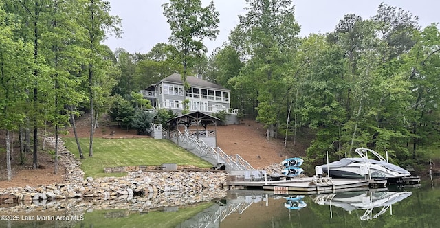 back of house with a water view and a lawn