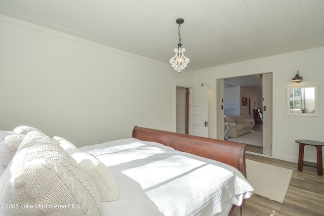 bedroom with a notable chandelier, crown molding, and hardwood / wood-style floors