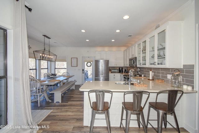 kitchen with white cabinets, appliances with stainless steel finishes, a kitchen breakfast bar, and kitchen peninsula