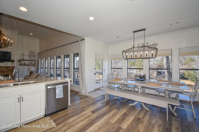 kitchen with decorative light fixtures, an inviting chandelier, sink, stainless steel dishwasher, and white cabinets