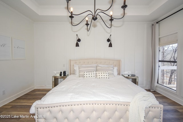 bedroom featuring a tray ceiling, dark wood-type flooring, and a notable chandelier