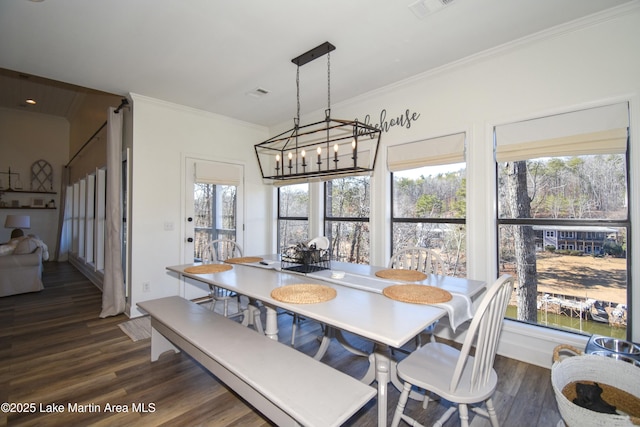 dining space featuring dark wood-type flooring, crown molding, and an inviting chandelier