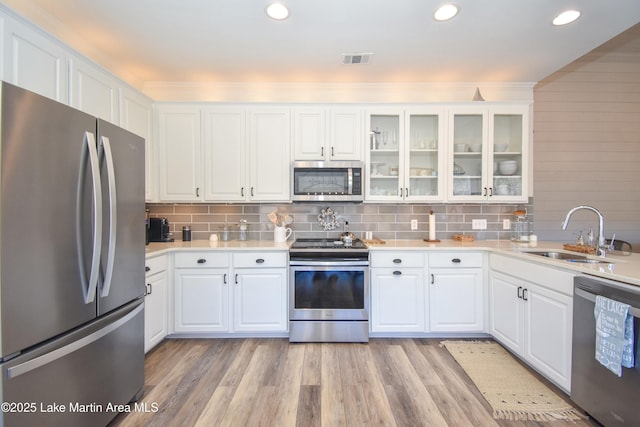 kitchen with sink, appliances with stainless steel finishes, white cabinets, and light hardwood / wood-style floors