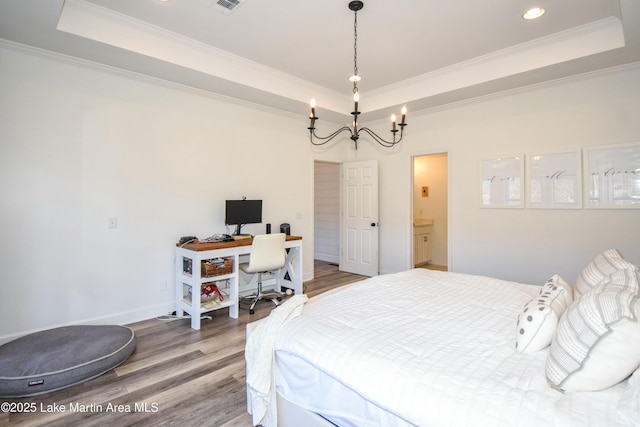 bedroom with hardwood / wood-style flooring, crown molding, an inviting chandelier, and a raised ceiling