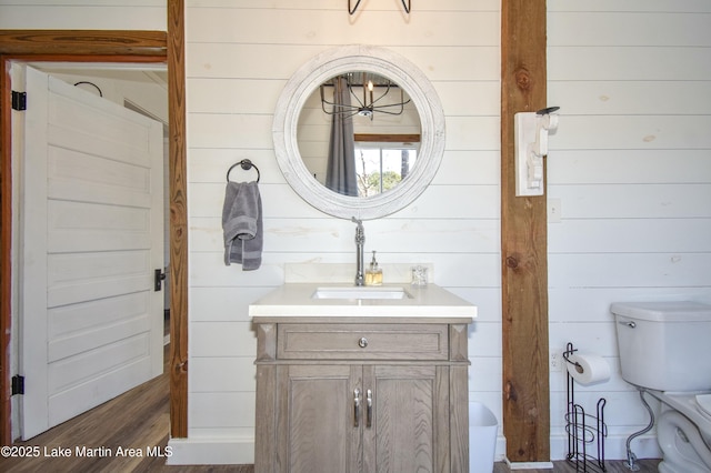 bathroom featuring wood walls, vanity, and toilet