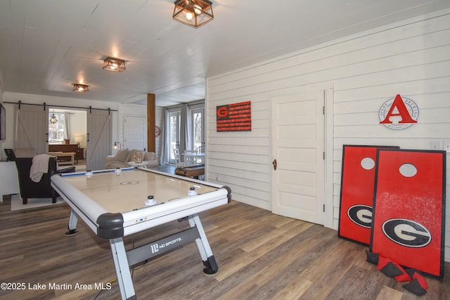 recreation room with a barn door, wood-type flooring, and a healthy amount of sunlight