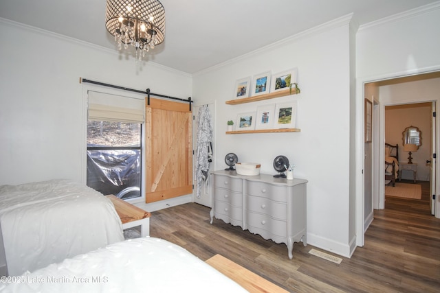 bedroom with dark hardwood / wood-style floors, a chandelier, a barn door, and ornamental molding