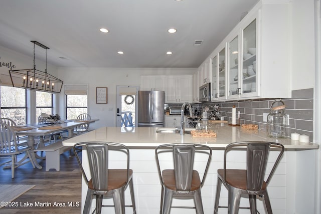 kitchen with sink, appliances with stainless steel finishes, white cabinets, a kitchen bar, and decorative backsplash