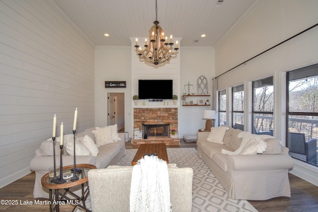 living room with a fireplace, hardwood / wood-style flooring, a towering ceiling, wood walls, and ornamental molding