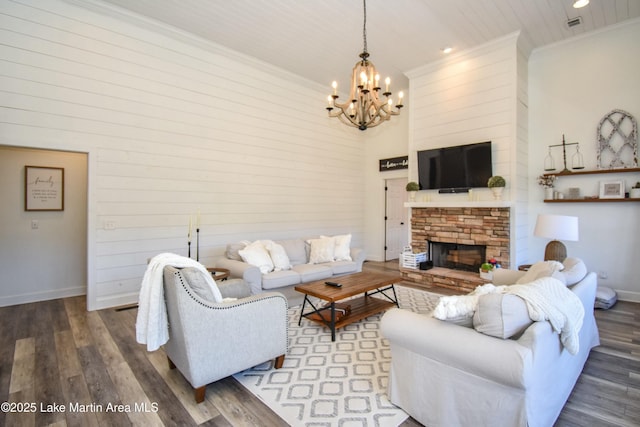 living room featuring a fireplace, ornamental molding, an inviting chandelier, and wood-type flooring