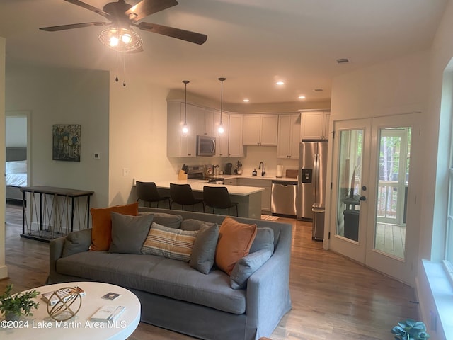 living room with light wood-type flooring, ceiling fan, and sink