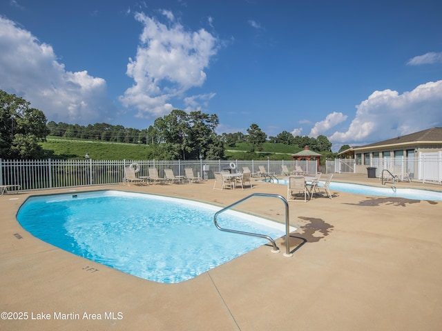 pool featuring fence and a patio area