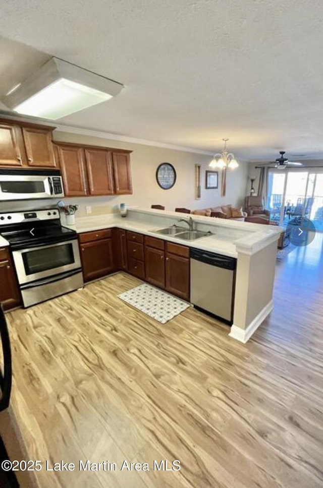 kitchen featuring a sink, open floor plan, light countertops, appliances with stainless steel finishes, and a peninsula