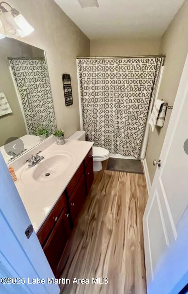 full bathroom featuring vanity, a shower with curtain, toilet, and wood finished floors