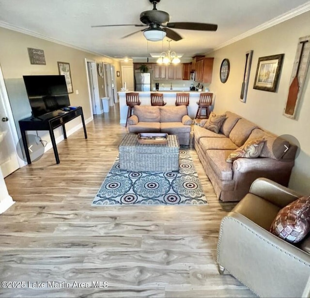 living room featuring baseboards, a ceiling fan, light wood-style floors, and crown molding