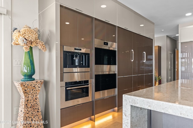 1020 Wake Robin, Eclectic, AL 36024 - kitchen featuring light stone countertops, modern cabinets, light wood-style flooring, and double oven