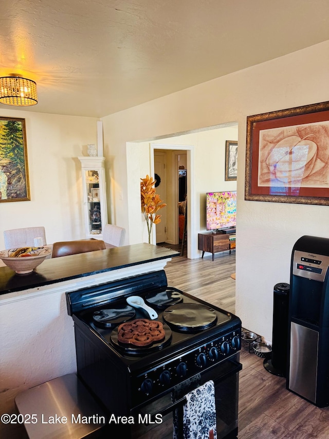 kitchen with black gas range and hardwood / wood-style floors