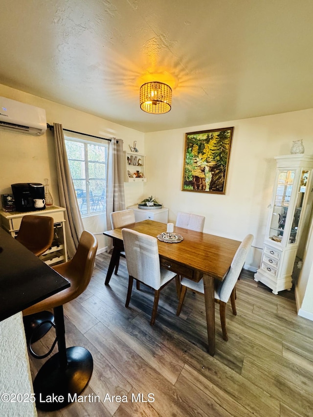 dining room with a notable chandelier, wood-type flooring, and an AC wall unit