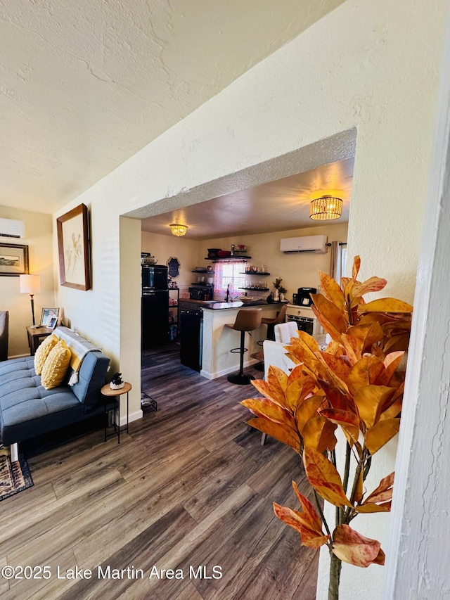 living room with hardwood / wood-style floors, a wall mounted AC, and a textured ceiling