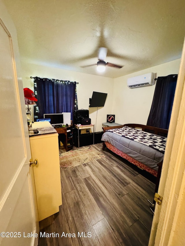 bedroom featuring hardwood / wood-style floors, a wall unit AC, a textured ceiling, and ceiling fan