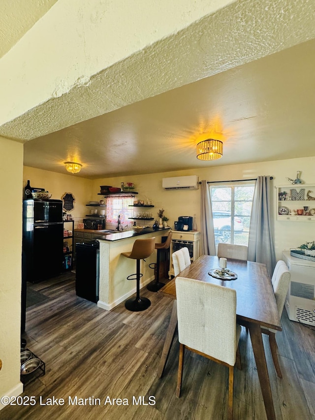 dining area with dark hardwood / wood-style floors, an AC wall unit, and a textured ceiling