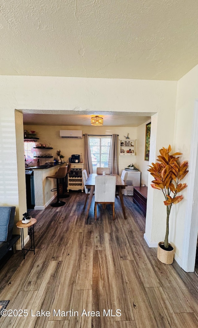 dining area featuring hardwood / wood-style flooring, a textured ceiling, and a wall unit AC